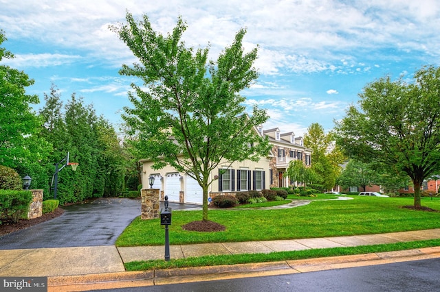 view of property hidden behind natural elements featuring a garage and a front yard