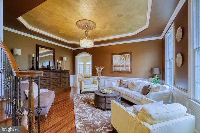 living room with hardwood / wood-style flooring, ornamental molding, and a raised ceiling