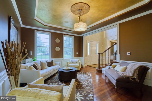 living room with hardwood / wood-style flooring, ornamental molding, and a tray ceiling