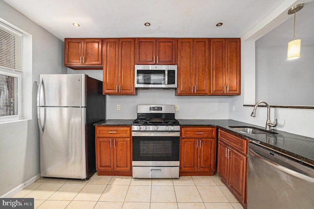 kitchen with pendant lighting, sink, dark stone counters, light tile patterned floors, and stainless steel appliances