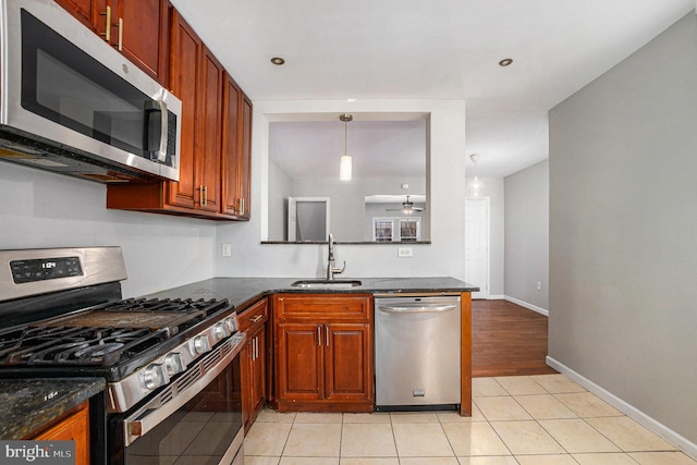 kitchen with sink, light tile patterned floors, appliances with stainless steel finishes, pendant lighting, and dark stone counters