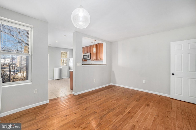 empty room with radiator heating unit and light hardwood / wood-style floors