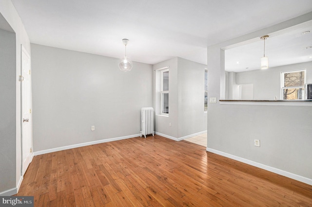 spare room featuring radiator heating unit and light hardwood / wood-style floors