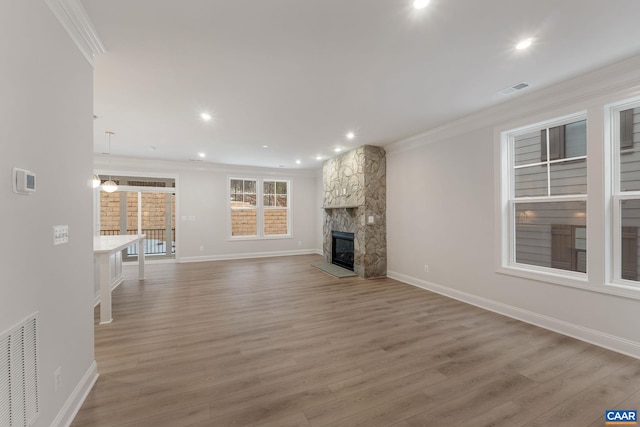 unfurnished living room featuring hardwood / wood-style floors, crown molding, and a fireplace