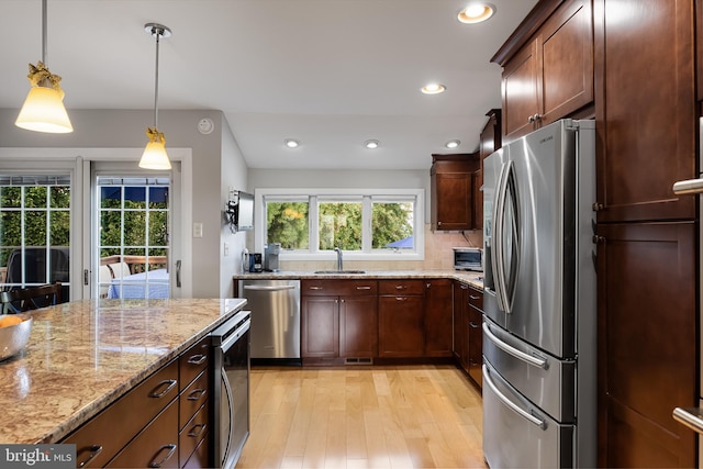 kitchen with appliances with stainless steel finishes, decorative light fixtures, sink, beverage cooler, and light stone counters