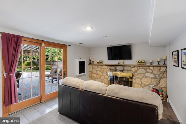 living room with a stone fireplace and light tile patterned floors