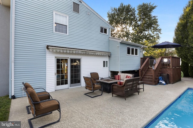 back of property featuring a pool side deck, an outdoor living space with a fire pit, and a patio