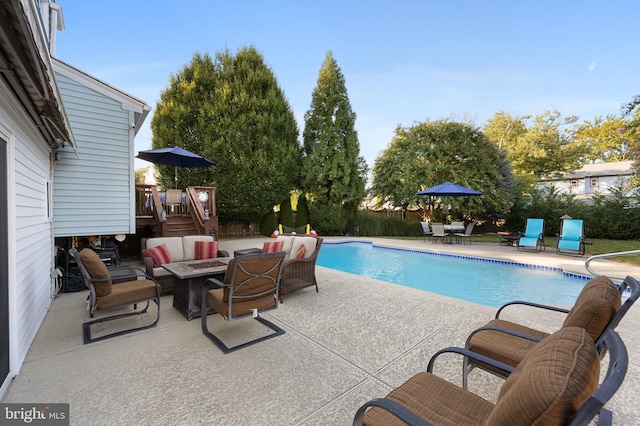 view of swimming pool featuring a patio and an outdoor living space with a fire pit