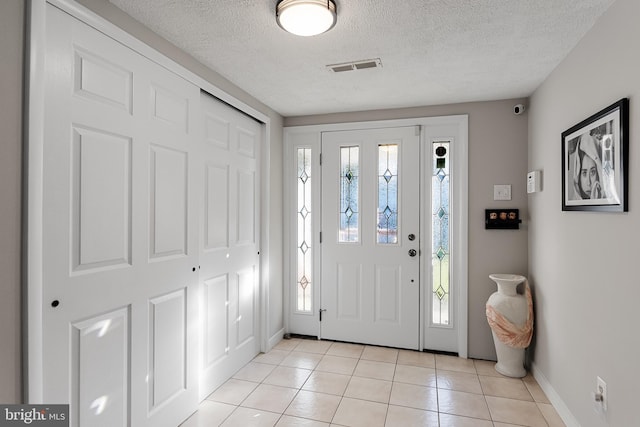 foyer entrance with light tile patterned floors and a textured ceiling