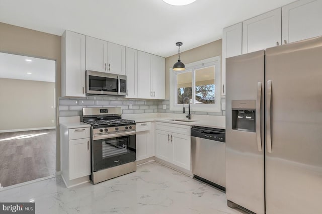 kitchen with sink, decorative light fixtures, appliances with stainless steel finishes, white cabinets, and backsplash