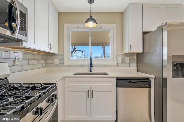 kitchen with tasteful backsplash, white cabinetry, sink, hanging light fixtures, and stainless steel appliances