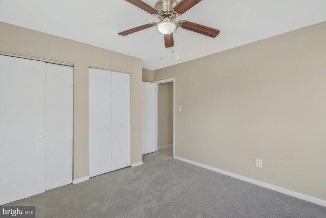 unfurnished bedroom with multiple closets, light colored carpet, and ceiling fan