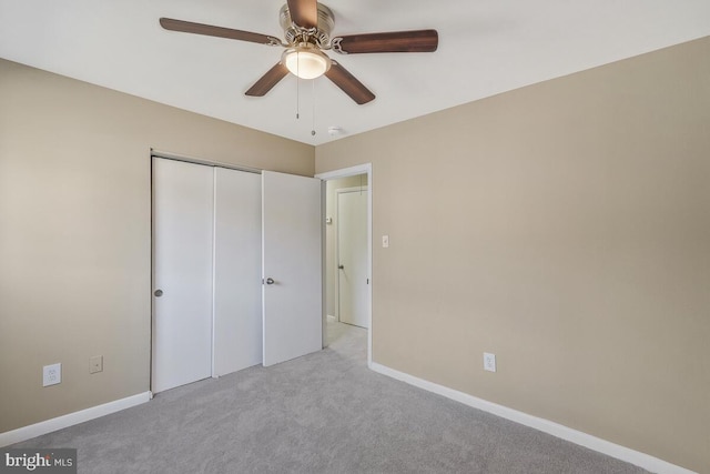 unfurnished bedroom featuring ceiling fan, light colored carpet, and a closet