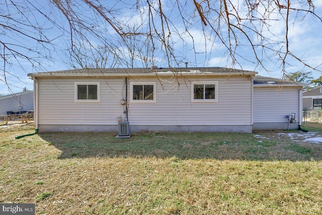 rear view of house featuring cooling unit and a lawn