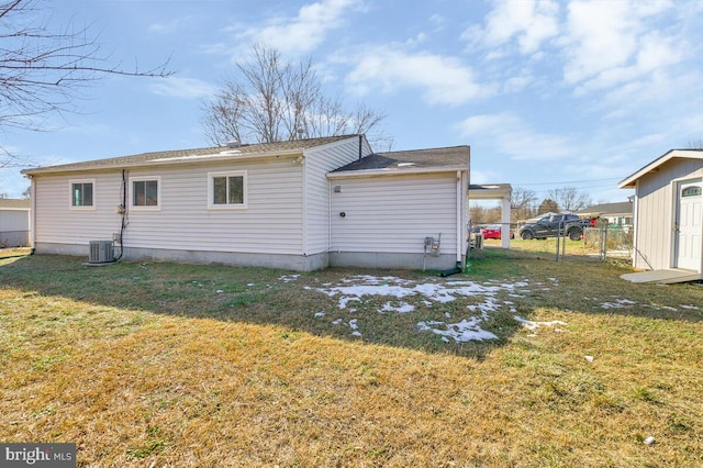 rear view of house featuring central AC unit and a lawn