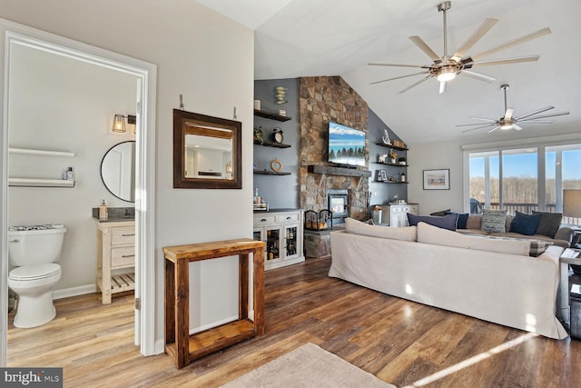 living room featuring vaulted ceiling, built in features, ceiling fan, a fireplace, and hardwood / wood-style floors