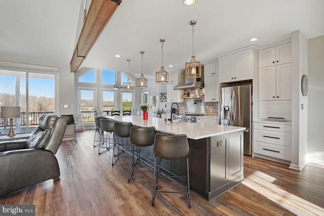 kitchen featuring a spacious island, a breakfast bar area, stainless steel fridge, pendant lighting, and white cabinets