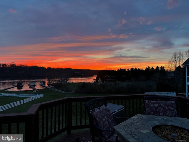 deck at dusk with a water view and an outdoor fire pit