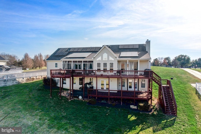 rear view of house featuring a yard, a deck, and solar panels