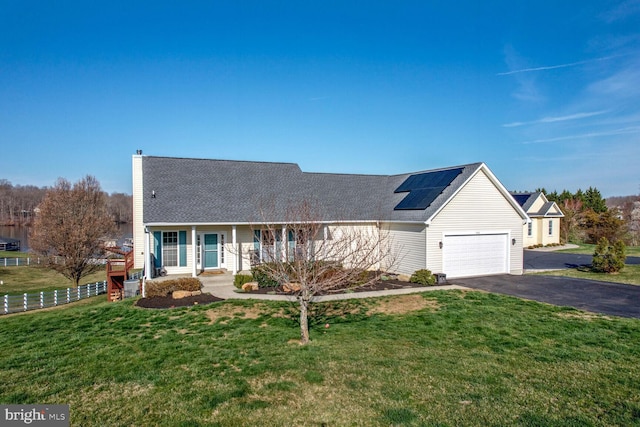 view of front of house featuring a garage, covered porch, a front lawn, and solar panels