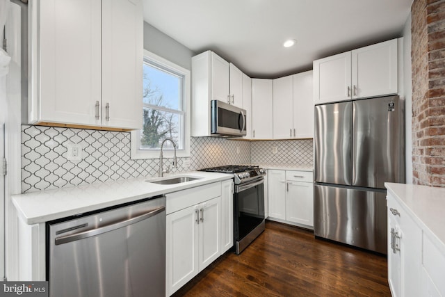 kitchen featuring white cabinets, appliances with stainless steel finishes, sink, backsplash, and dark hardwood / wood-style floors