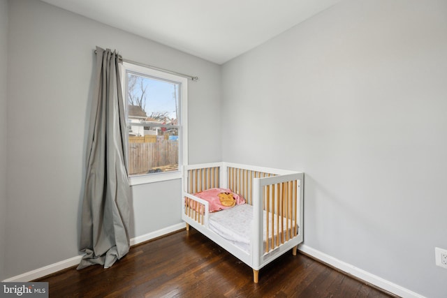 bedroom featuring dark wood-type flooring and a crib