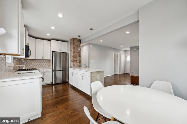 kitchen with white cabinetry, appliances with stainless steel finishes, backsplash, hanging light fixtures, and sink