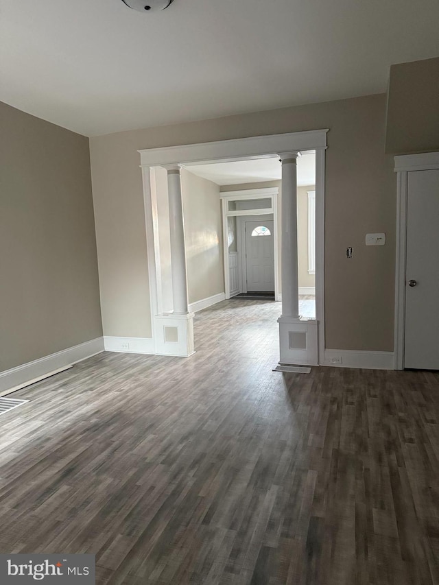 interior space with ornate columns and dark hardwood / wood-style floors