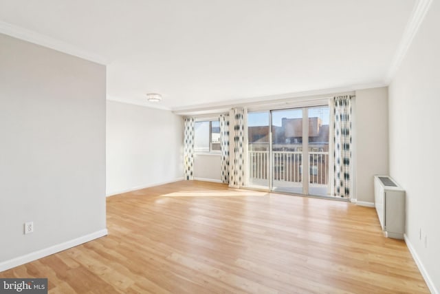 spare room with light wood-type flooring, radiator heating unit, and crown molding