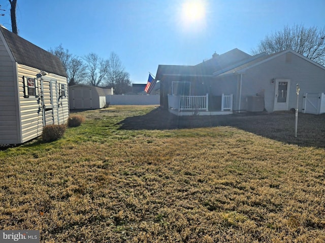 view of yard with central air condition unit, an outdoor structure, fence, and a shed