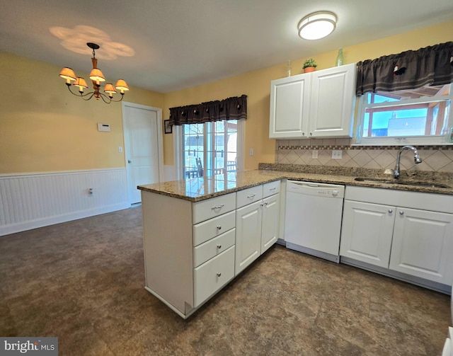 kitchen with a wainscoted wall, a peninsula, a sink, white cabinetry, and dishwasher