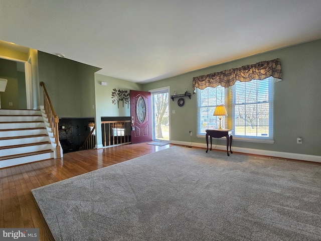 unfurnished living room with stairs, wood finished floors, and baseboards