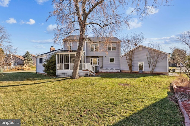 back of house featuring a lawn, a chimney, and a sunroom