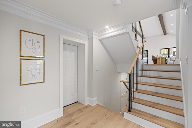 stairway featuring vaulted ceiling with beams, crown molding, and hardwood / wood-style floors