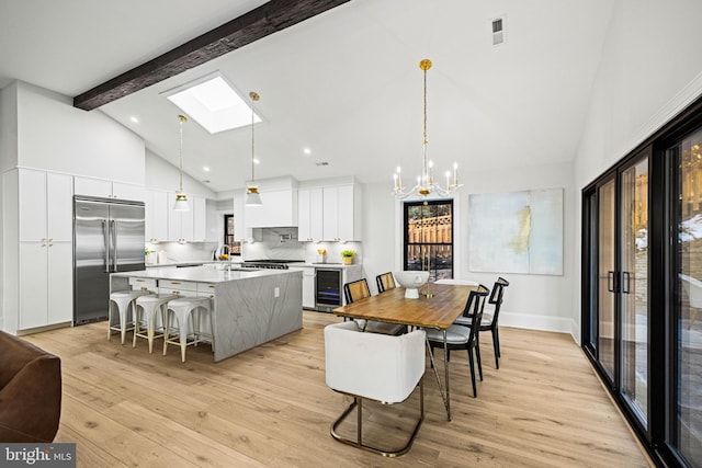 kitchen featuring stainless steel built in refrigerator, white cabinetry, beamed ceiling, beverage cooler, and pendant lighting