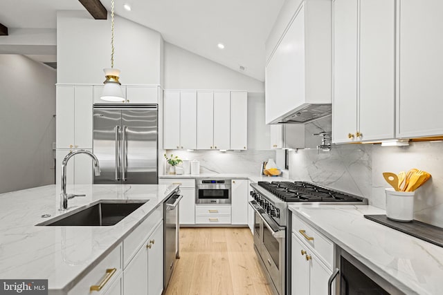 kitchen featuring light stone countertops, high end appliances, custom exhaust hood, white cabinetry, and sink