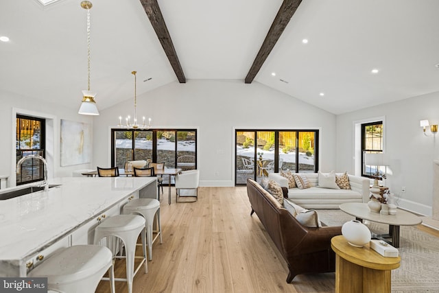 living room with a notable chandelier, high vaulted ceiling, light wood-type flooring, beam ceiling, and sink