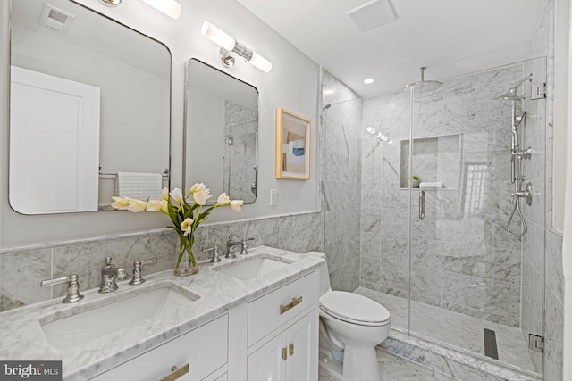 bathroom with tile walls, vanity, a shower with shower door, and toilet