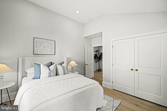 bedroom with vaulted ceiling, a closet, and light hardwood / wood-style floors