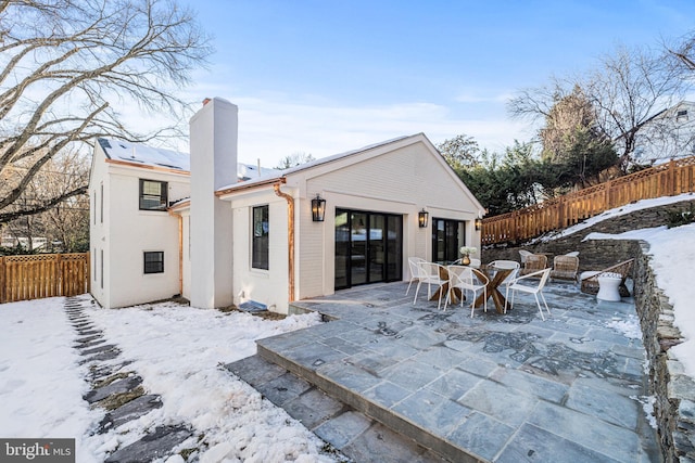 snow covered house featuring a patio area