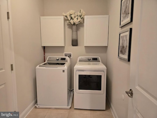 laundry room featuring light tile patterned floors, cabinets, and washing machine and clothes dryer