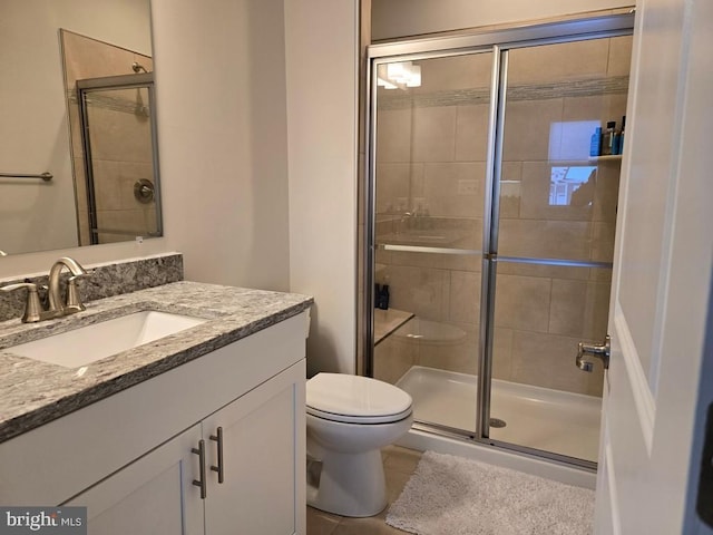 bathroom featuring vanity, tile patterned floors, a shower with door, and toilet