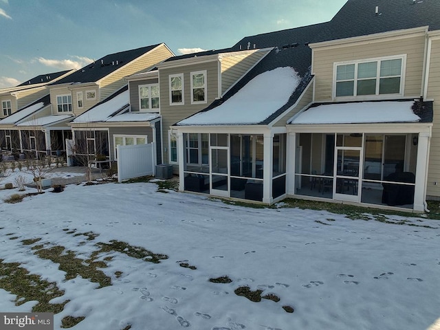 snow covered house featuring a sunroom and central air condition unit