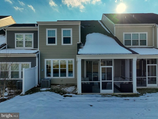 snow covered rear of property featuring a sunroom