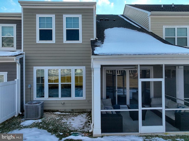 snow covered property featuring a sunroom and central AC