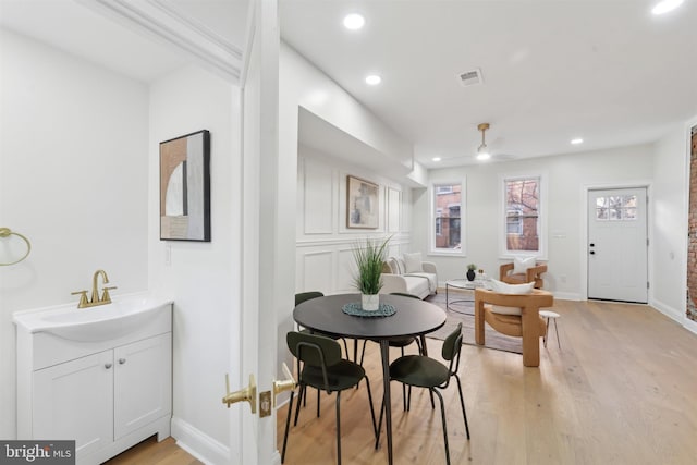 dining space featuring ceiling fan, light hardwood / wood-style floors, and sink