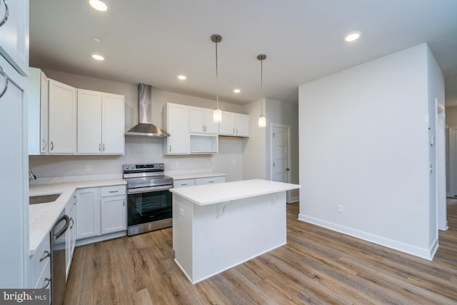 kitchen with white cabinetry, wall chimney range hood, hanging light fixtures, and appliances with stainless steel finishes