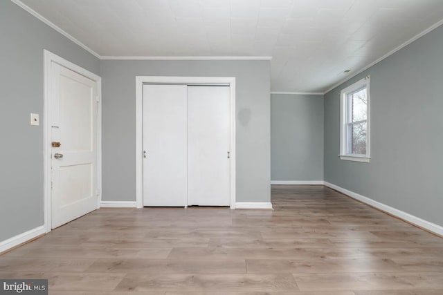 unfurnished bedroom with crown molding, light wood-type flooring, and a closet