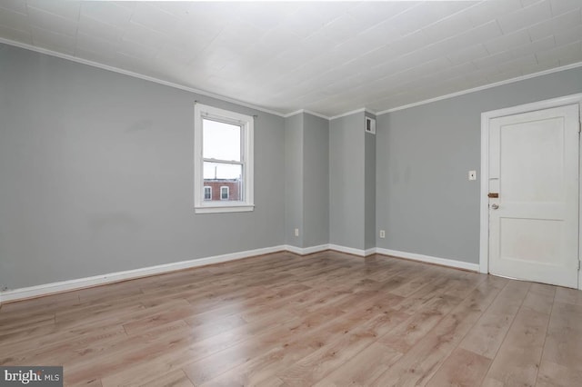 spare room featuring ornamental molding and light hardwood / wood-style floors