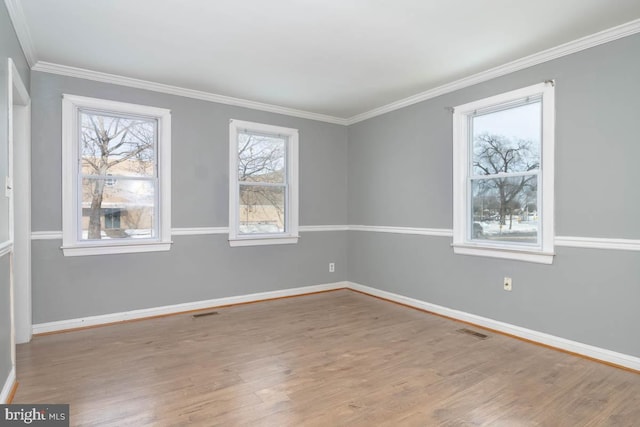 empty room with ornamental molding and light hardwood / wood-style floors